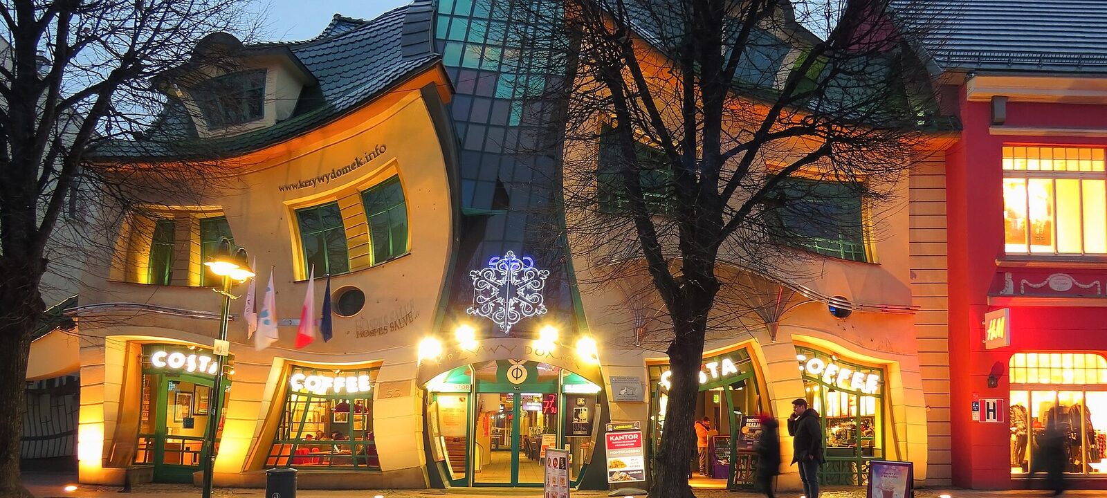 Krzywy Domek i Sopot, ett hus med böjda väggar och sneda fönster, upplyst i skymningen